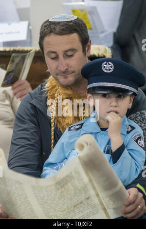 Elkana, Israele. 20 Mar, 2019. La lettura del libro di Ester in una Sinagoga durante la festa ebraica di Purim. In questa vacanza ebrei traditionaly vestito in costumi, leggere la chiocciola di Esther, una storia su un anti-ebraica complotto fallito nell antica Persia e fare un racket ogni volta che il nome di Haman, l'antagonista principale, è menzionato. Credito: Yagil Henkin/Alamy Live News Foto Stock