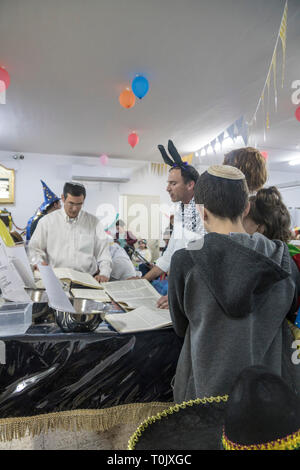 Elkana, Israele. 20 Mar, 2019. La lettura del libro di Ester in una Sinagoga durante la festa ebraica di Purim. In questa vacanza ebrei traditionaly vestito in costumi, leggere la chiocciola di Esther, una storia su un anti-ebraica complotto fallito nell antica Persia e fare un racket ogni volta che il nome di Haman, l'antagonista principale, è menzionato. Credito: Yagil Henkin/Alamy Live News Foto Stock