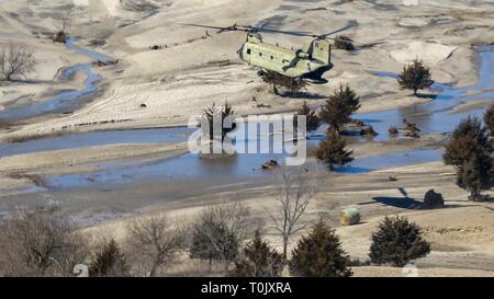 Il Nebraska Esercito Nazionale soldati di guardia lo scarico balle di fieno da un CH-47 elicottero Chinook per bovini cordato dalle inondazioni, 20 marzo 2019 Richland, Nebraska. Centro storico Le inondazioni causate dalla rapida fusione di nevicata record sweep attraverso le comunità rurali nel Nebraska e Iowa uccidendo almeno quattro persone nelle pianure e Midwest. Foto Stock