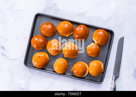 Brioche mini hamburger i panini su una teglia da forno. Foto Stock