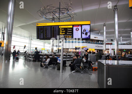 Inghilterra aeroporto di Heathrow Terminal due passeggeri in attesa per i voli in sala partenze con negozi duty free e ristoranti Foto Stock