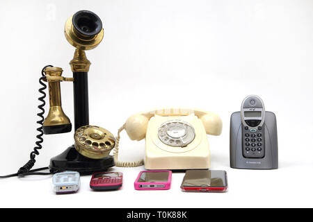 Una collezione di telefoni vecchio e nuovo - candelabro telefono, manopola diretta, telefono cordless e cellulari - Nokia 3310, Nokia C3, iPhone 5 Foto Stock