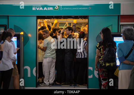 Le persone che entrano nel skytrain, treno di Bangkok, Tailandia in modo ordinato ma molto spinti modo Foto Stock