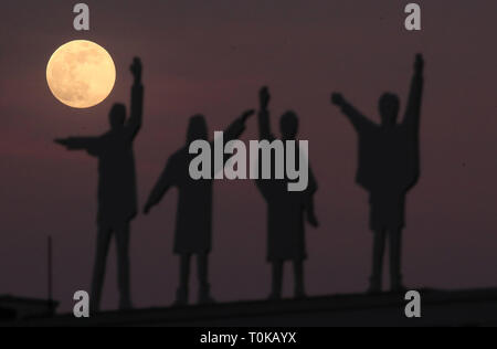 La luna sorge alle spalle di sagome dei Beatles, dal film Aiuto, su Penny Lane in Liverpool. Foto Stock