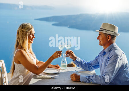Adulto Giovane avente la cena e un bicchiere di vino in un ristorante sullo sfondo del mare Foto Stock