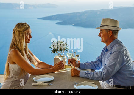 Adulto Giovane avente la cena e un bicchiere di vino in un ristorante sullo sfondo del mare Foto Stock