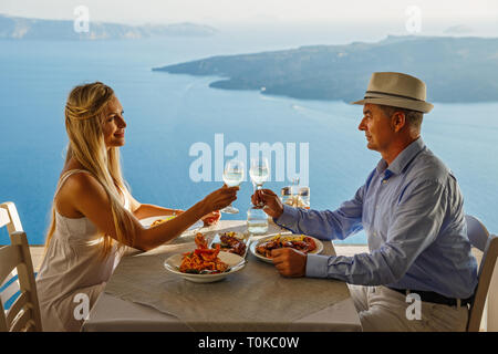 L uomo e la donna a cena in un ristorante sullo sfondo del mare - Santorini Island, Grecia Foto Stock