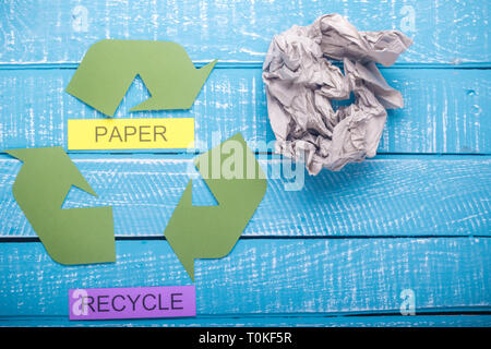 Concetto di riciclo che mostra il verde del logo di riciclo con carta & recylce su un blu sfondo spiovente Foto Stock