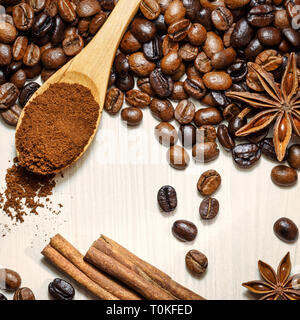Foto Piazza di chicchi di caffè tostati con spezie aromatiche anice stellato e bastoncini di cannella sul tavolo luminoso, vista dall'alto. Foto Stock
