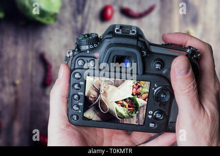 L'uomo prendendo foto del messicano tradizionale Tortilla avvolgere con verdure e grigliate di carne di pollo sulla tavola di legno Foto Stock
