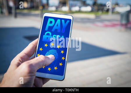 Mano utilizzando uno smartphone e pagare online.forte autenticazione cliente o SCA approvati dall'UE riveduto direttiva sui servizi di pagamento o PSD2 Foto Stock