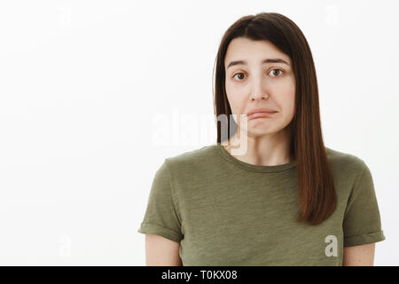 Spiacenti. Ritratto di insicuro colpevole e timido carino brunette ondeggiare mento e labbra inferiore, rendendo lo spallamento spallucce come l' errore, posa triste e Foto Stock