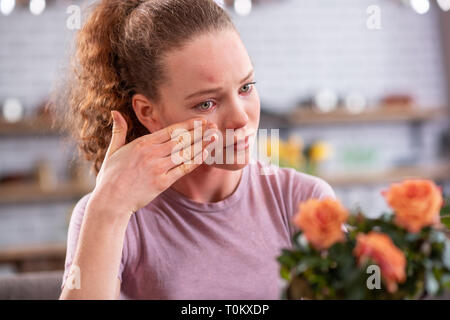 Attraente curly-donna dai capelli con luce verde occhi avente teardrops Foto Stock