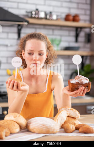 Addolorato donna giovane azienda con polpettine di pane in entrambe le mani Foto Stock