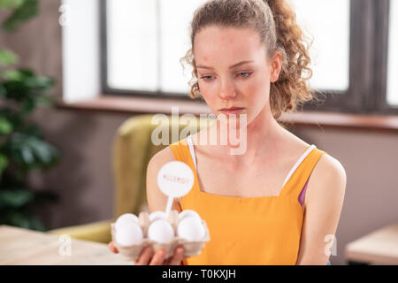 Turbato dai lunghi capelli ragazza attraente avente reazione allergica sulle uova Foto Stock