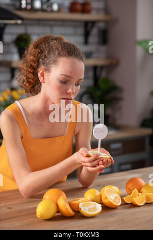 Con i capelli lunghi curly ragazza portando la metà del limone con notifica in stick Foto Stock