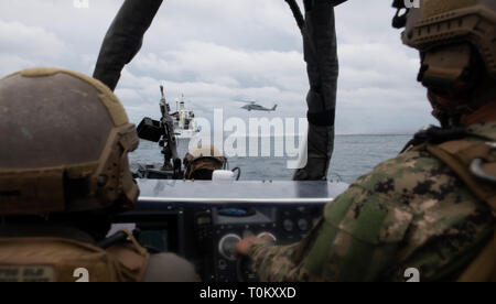 190319-N-HD110-0669 OCEANO PACIFICO (19 marzo 2019) marinai attaccato all assalto unità artigianali (ACU) 1 osservare un MH-60S Sea Hawk approccio elicottero nave MV ATLS-9701 durante una visita, scheda, ricerca e sequestro esercizio condotta dalla harpers Ferry-classe dock anfibio sbarco nave USS harpers Ferry (LSD 49). Harpers Ferry è in corso conducendo le operazioni di routine come una parte di USS Boxer anfibio gruppo pronto (ARG) nell'Oceano Pacifico orientale. (U.S. Foto di Marina di Massa lo specialista di comunicazione di terza classe Danielle A. Baker) Foto Stock