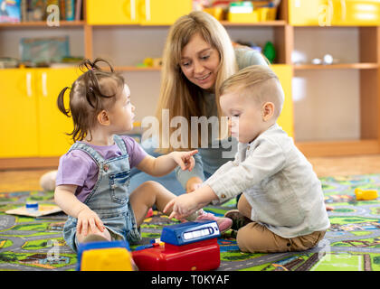 Babysitter gioca con neonati in vivaio o kindergarten Foto Stock