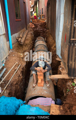 Cambogia, zone di Mondulkiri Provincia, Sen Monorom, area di mercato, gli uomini costruendo nuovi scaricare attraverso il vicolo Foto Stock