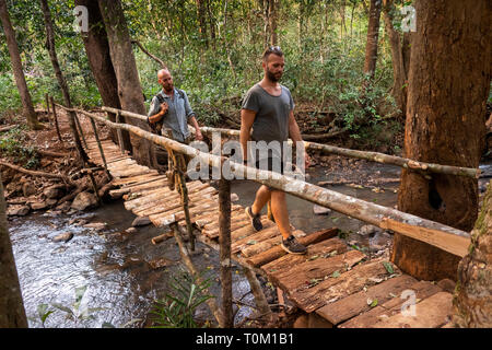 Cambogia, zone di Mondulkiri Provincia, Sen Monorom, elefante progetto Valle, membro del personale volontario e attraversando ponte sul fiume della foresta Foto Stock