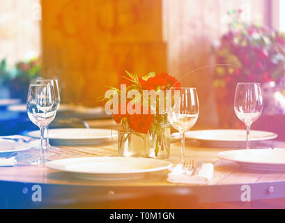 Splendido tavolo nel ristorante con elettrodomestici, bicchieri e rose rosse in un vaso Foto Stock