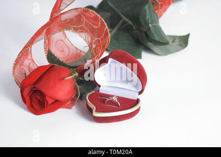 Gli anelli di nozze ed una rosa rossa su sfondo bianco.foto con spazio di copia Foto Stock