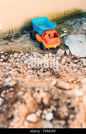 Carrello giocattolo e pila di ghiaia nel cortile posteriore Foto Stock