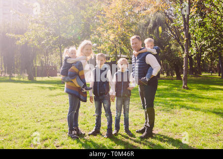 Tema famiglia svago attivo al di fuori in natura. grande famiglia caucasica con quattro figli. Mamma e papà attivamente rilassante. Goditi la vita nel parco vicino a casa Foto Stock