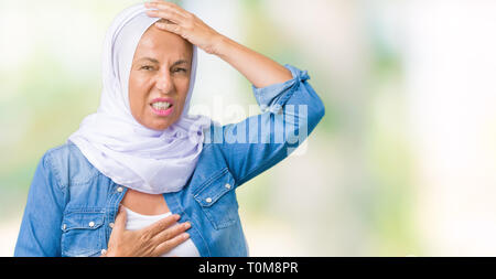 La mezza età araba orientale donna che indossa arabian hijab su sfondo isolato di toccare la fronte per la malattia e la febbre, influenza e raffreddori, virus malati Foto Stock