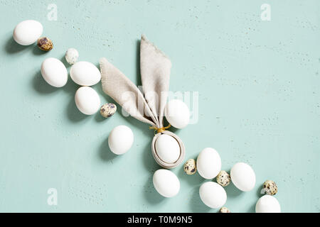 Pollo e uova di quaglia con orecchie di coniglietto della biancheria igienico sul blu tabella strutturata, composizione di Pasqua, vista dall'alto Foto Stock