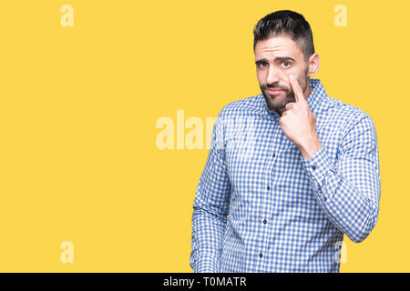 Giovane uomo bello su sfondo isolata rivolta verso l'occhio ti guarda gesto, espressione sospette Foto Stock