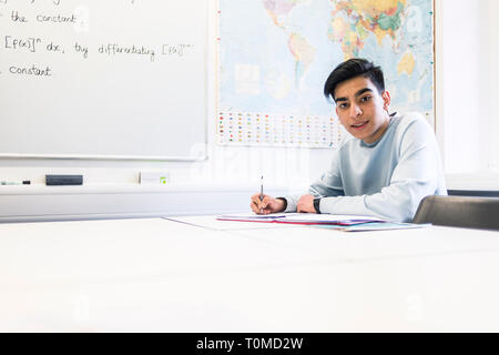 Uno studente internazionale studi hard in una classe in un College di Cambridge Foto Stock