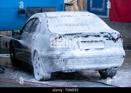 Lavaggio auto nero con schiuma attiva. Lavaggi uomo macchina di schiuma. Nello stato di Washington per auto Macchina di lavaggio alla stazione Foto Stock