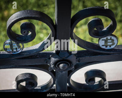 Golden moneta di bit su acciaio arrugginito antica recinzione in una giornata di sole. Foto Stock