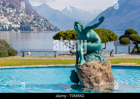 Una fontana al centro del lago di Lugano con una bella statua in medio di acqua blu nella parte italiana della Svizzera Foto Stock
