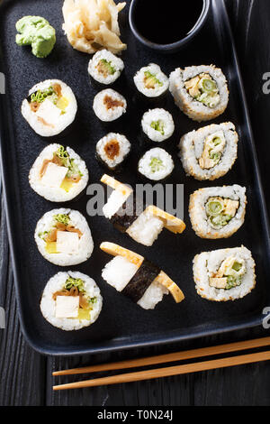 Rulli giapponese, Hosomaki Uramaki, maki e nigiri, Tamagoyaki con vari ripieni di close-up su una piastra sul tavolo. Verticale in alto vista da sopra Foto Stock
