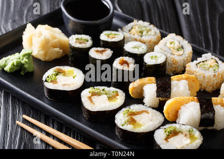 Giapponese set di rulli con tonno, tofu, anguilla, avocado, tamago closeup su una piastra sul tavolo orizzontale. Foto Stock