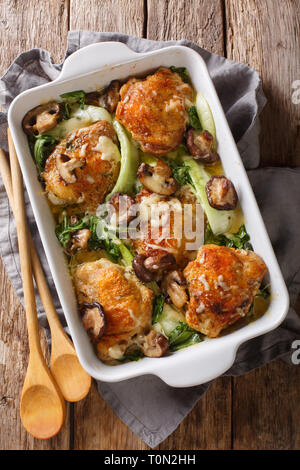 Cotto al forno cosce di pollo con baby bok choi, formaggio e funghi vicino sul tavolo. verticale in alto vista da sopra Foto Stock