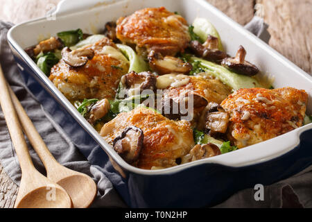 Cibo sano e cotto al forno cosce di pollo con baby bok choi, funghi shiitake e salsa al formaggio in uno stile rustico closeup sul tavolo orizzontale. Foto Stock