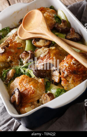 Cotto al forno cosce di pollo con baby bok choi, formaggio e funghi vicino sul piano verticale. Foto Stock