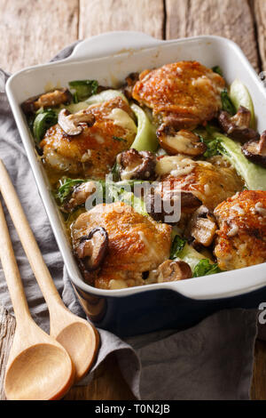 Frittura di cosce di pollo con baby bok choi, formaggio e funghi in stile asiatico vicino sul piano verticale. Foto Stock