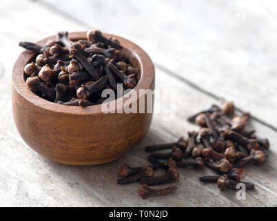 I chiodi di garofano in una piccola ciotola di legno shot nella finestra luce sfondo sfocato ad ad uno spazio di copia Foto Stock