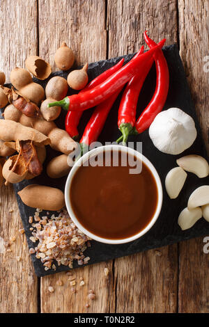 Asian preparata di fresco e salsa di tamarindo con ingredienti di close-up su di un tavolo di legno. Verticale in alto vista da sopra Foto Stock