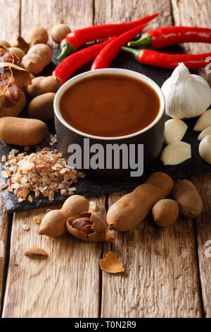 Asian preparata di fresco e salsa di tamarindo con ingredienti di close-up su una tavola di legno verticale. Foto Stock