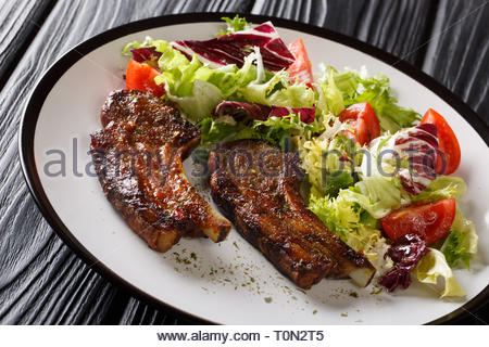 Porzione di costolette fritte con verdura fresca insalata di close-up su una piastra sul tavolo orizzontale. Foto Stock