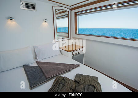 Un letto doppio nella cabina di un privato di lusso yacht a motore con vista mare Foto Stock