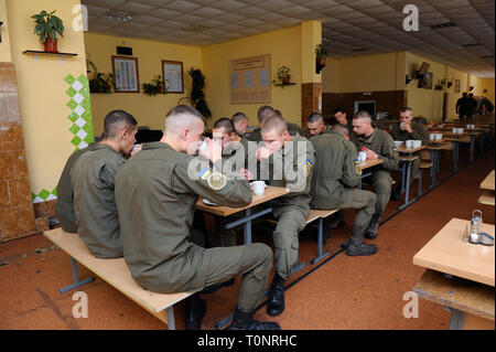 In corrispondenza di un pasticcio hall: soldati seduti al set-tabelle e mangiare. Novo-Petrivtsi base militare, Ucraina. Novembre 12, 2018 Foto Stock