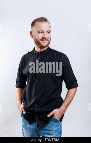 Ritratto di un bel giovane uomo sorridente su sfondo grigio Foto Stock