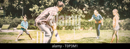 La famiglia felice a giocare a cricket in posizione di parcheggio Foto Stock