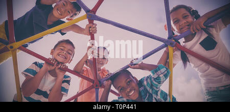 Ritratto di felice schoolkids guardando attraverso la cupola scalatore Foto Stock